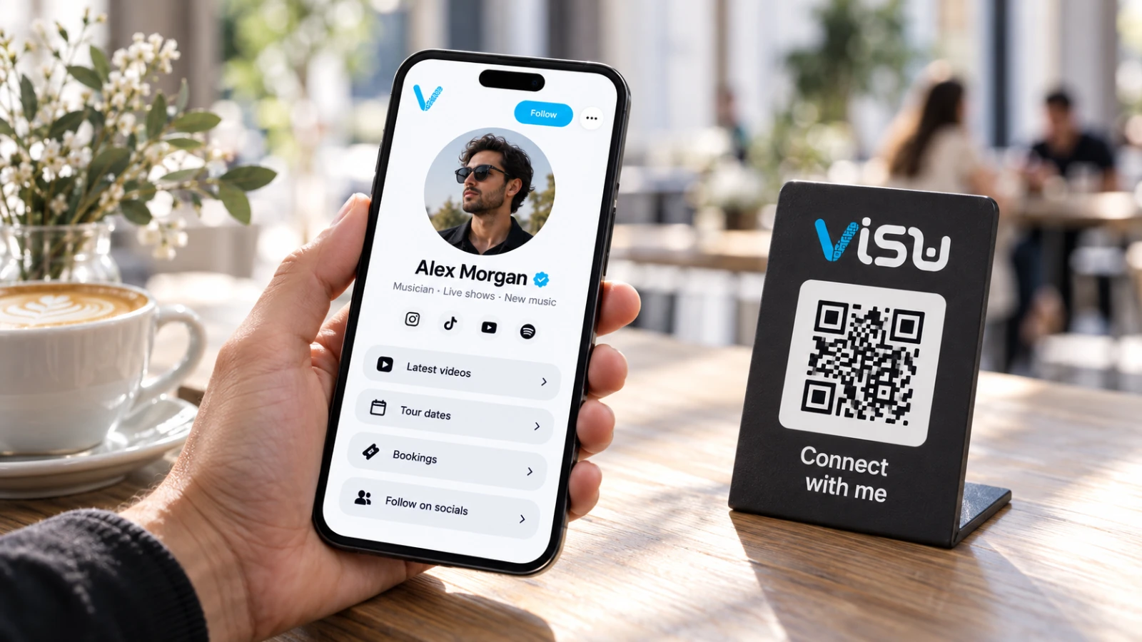A hand holding a VISU Link profile next to a VISU QR stand on a café table