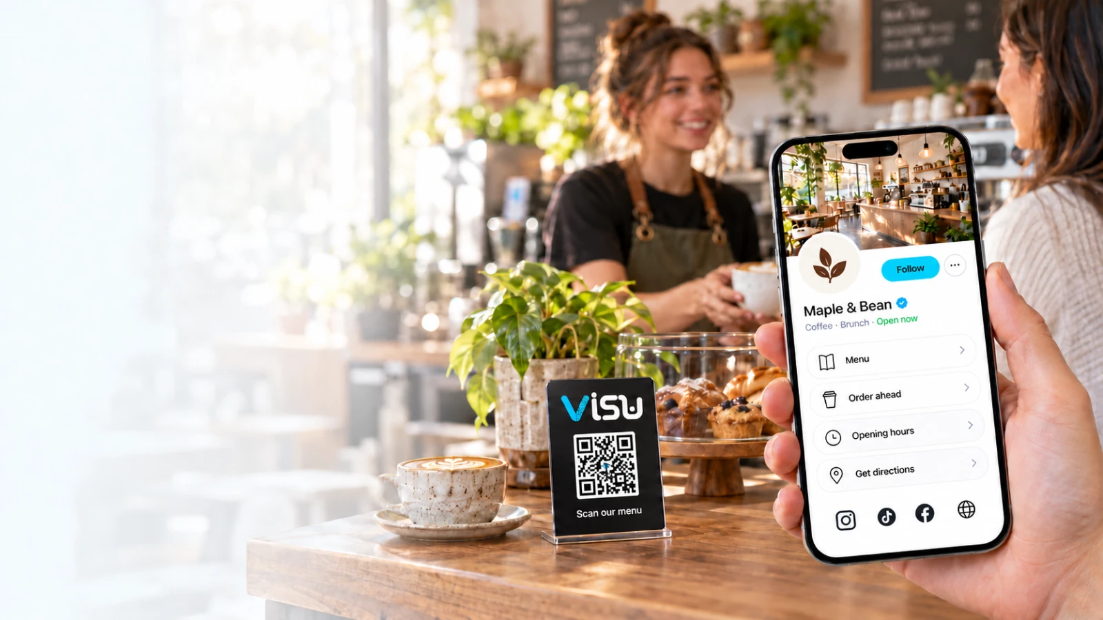 A hand holding the VISU Link profile of a café next to a VISU QR stand on the counter
