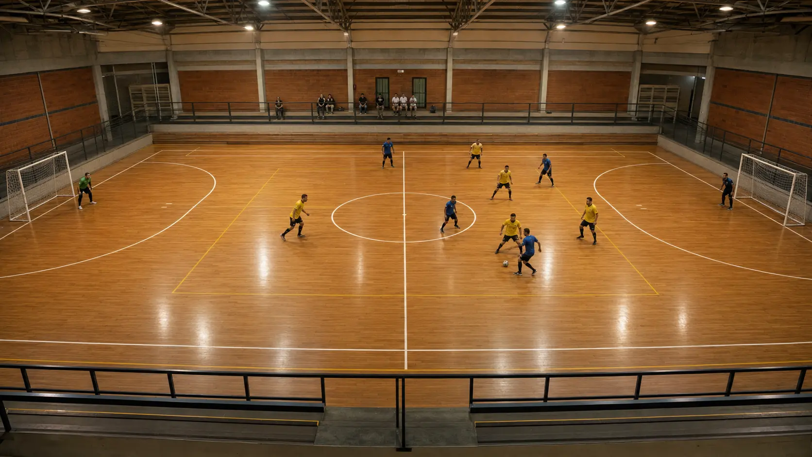 Cancha techada de futsal vista desde una posición elevada en la mitad de la cancha durante un partido