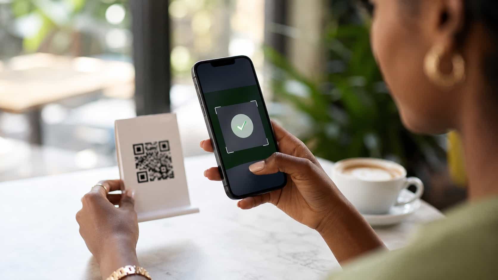 Hands holding a phone scanning a QR code on a cafe table card with an abstract campaign reward screen