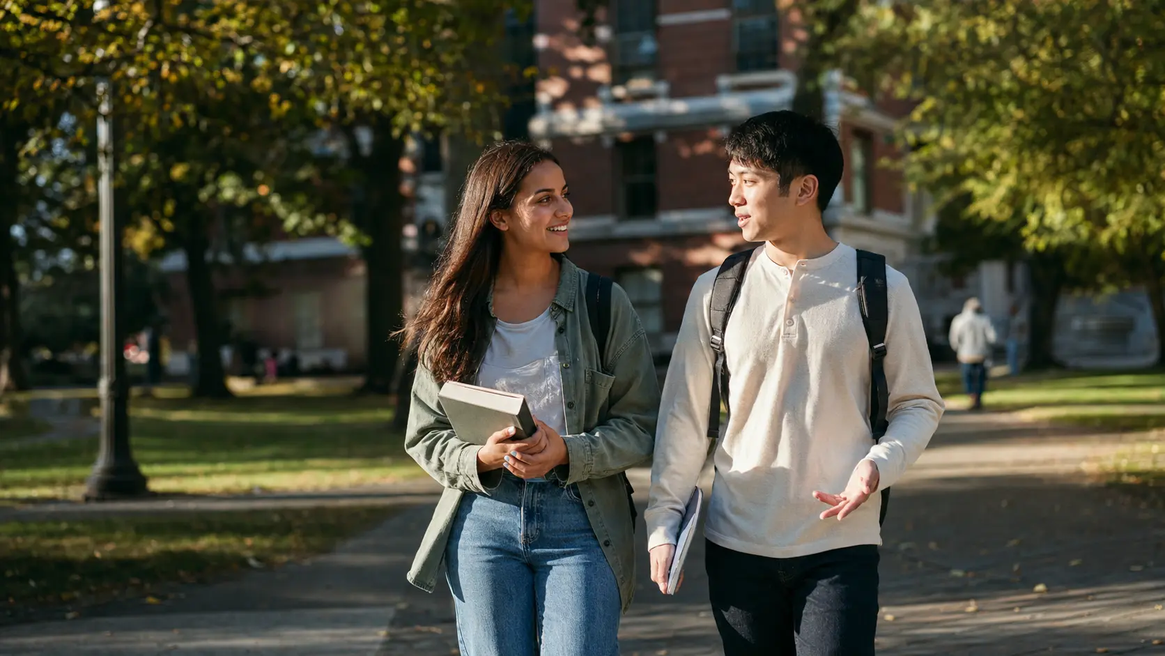 Two students walking across a university campus together with backpacks