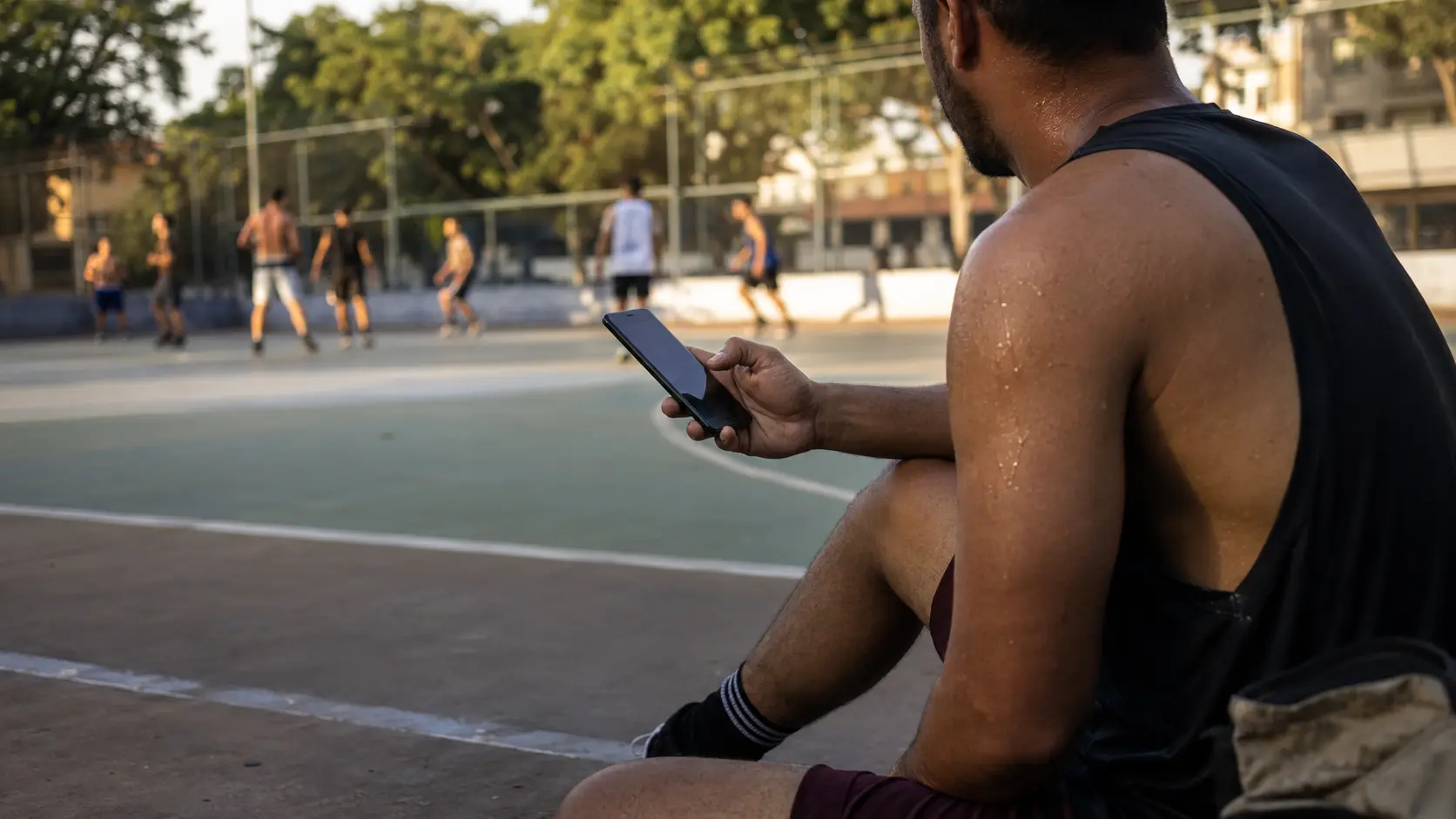 Phone on a small tripod at the edge of a court, bag and bottle beside it