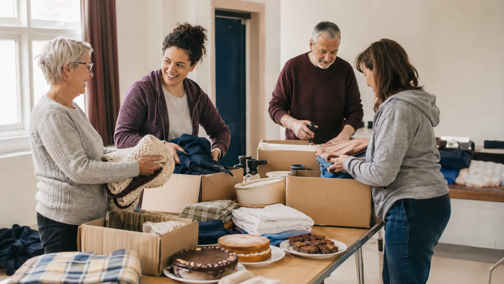 Church volunteers organising donated goods and baked items on a community hall table