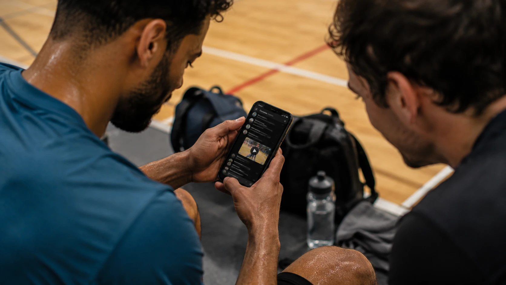 Jugadores amateurs alrededor de un celular en el grupo mirando un clip del partido que acaban de jugar