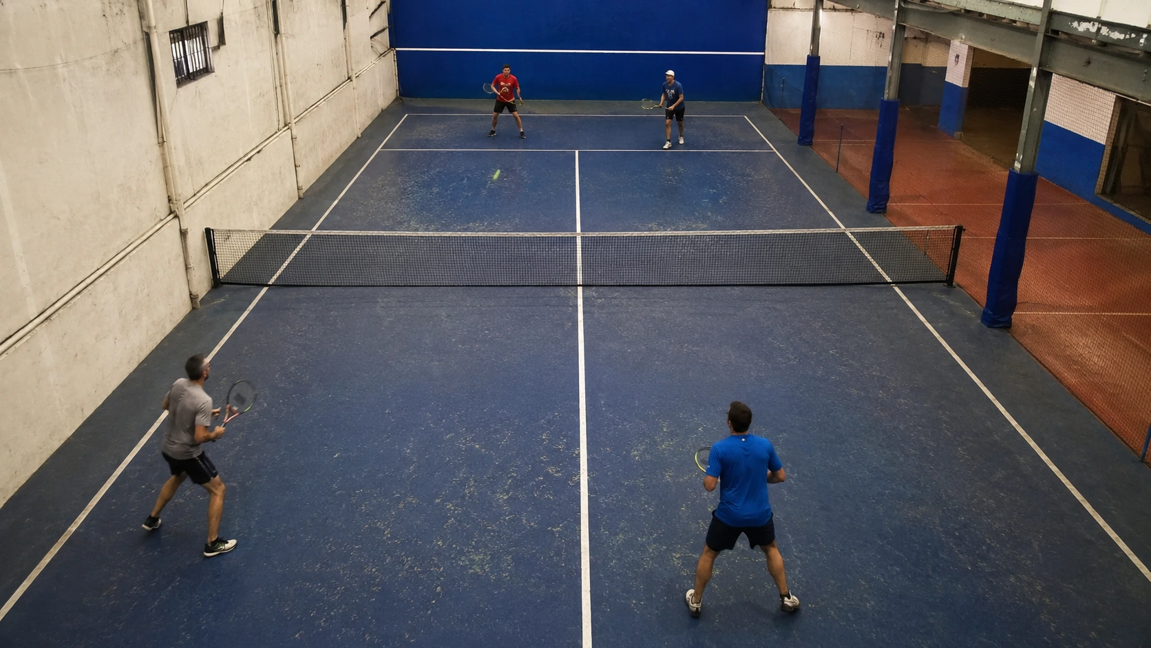 Fixed camera above an amateur court recording a full match with players in motion below