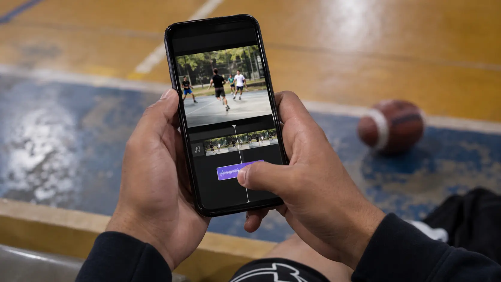Pantalla de edición en un celular mostrando un clip deportivo corto con una pista de música agregándose debajo de la línea de tiempo