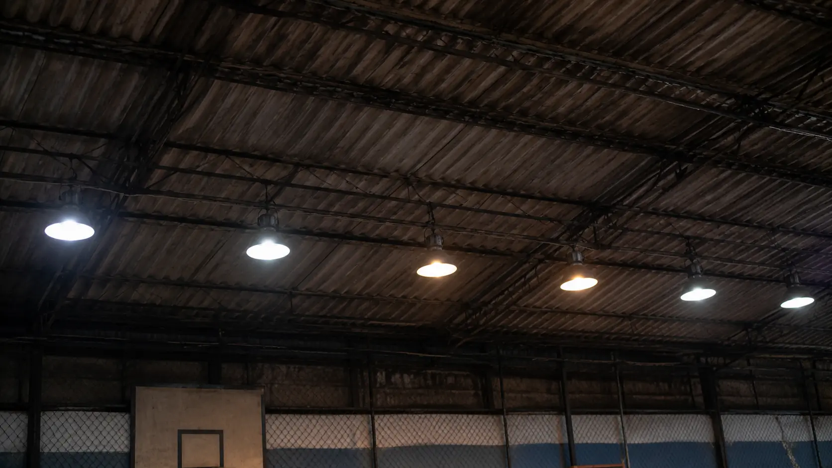 Jugador grabando desde el borde de una cancha techada con las luminarias detrás de él
