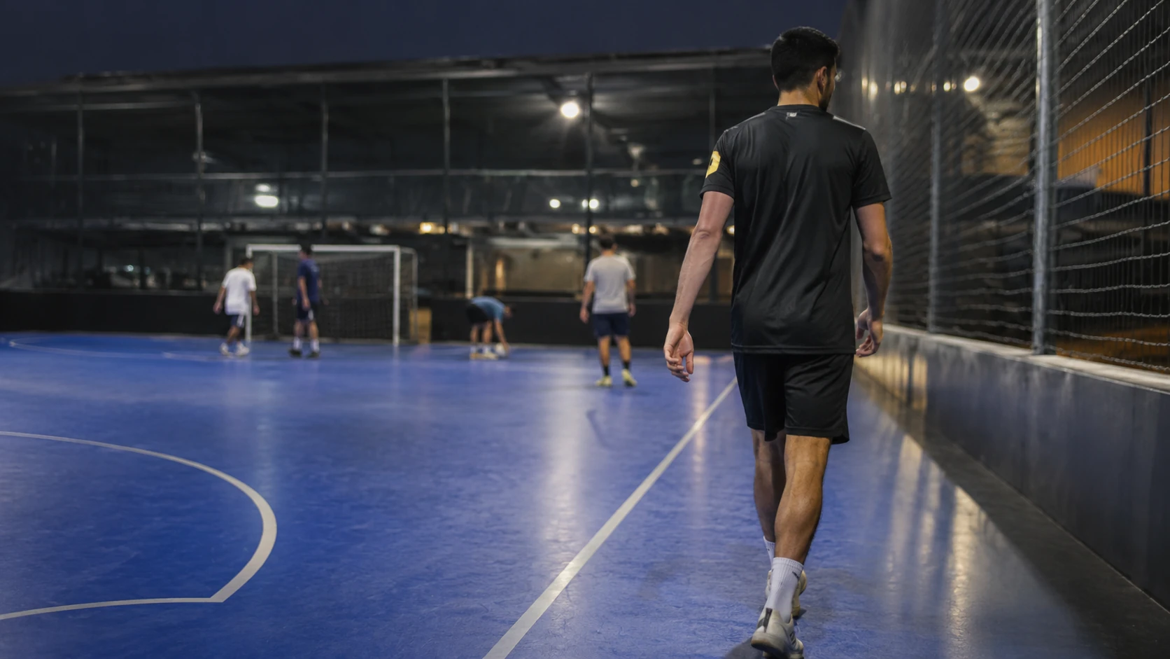 Amateur player walking toward the edge of the court after a point while the other players reset behind