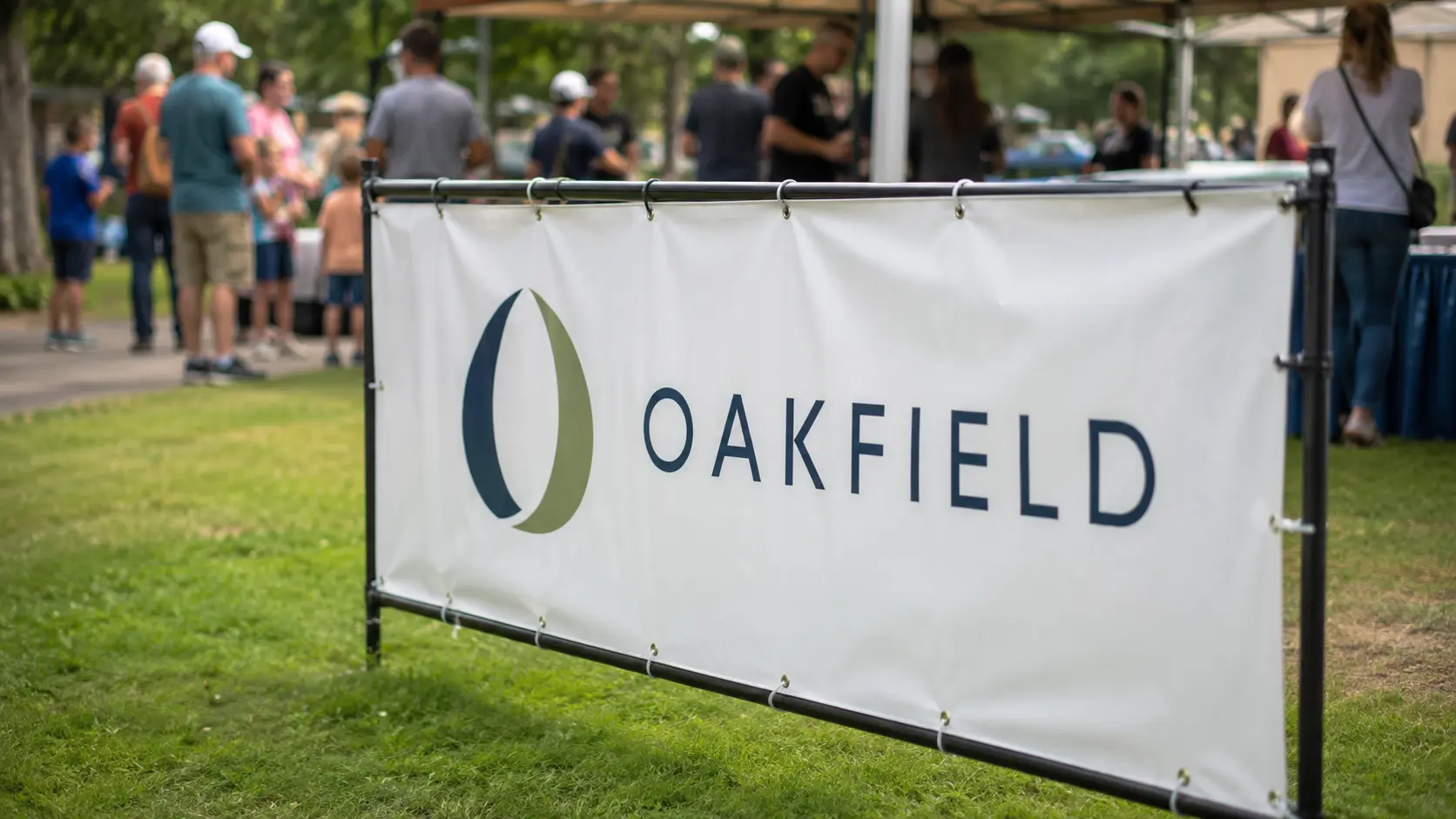 Plain sponsor logo banner displayed at a community fundraising event with attendees in the background