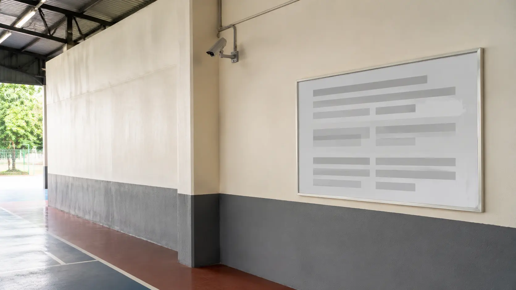 Pared lateral de una cancha cubierta con un aviso genérico sin texto legible y una pequeña cámara fija instalada en lo alto sobre el área de juego