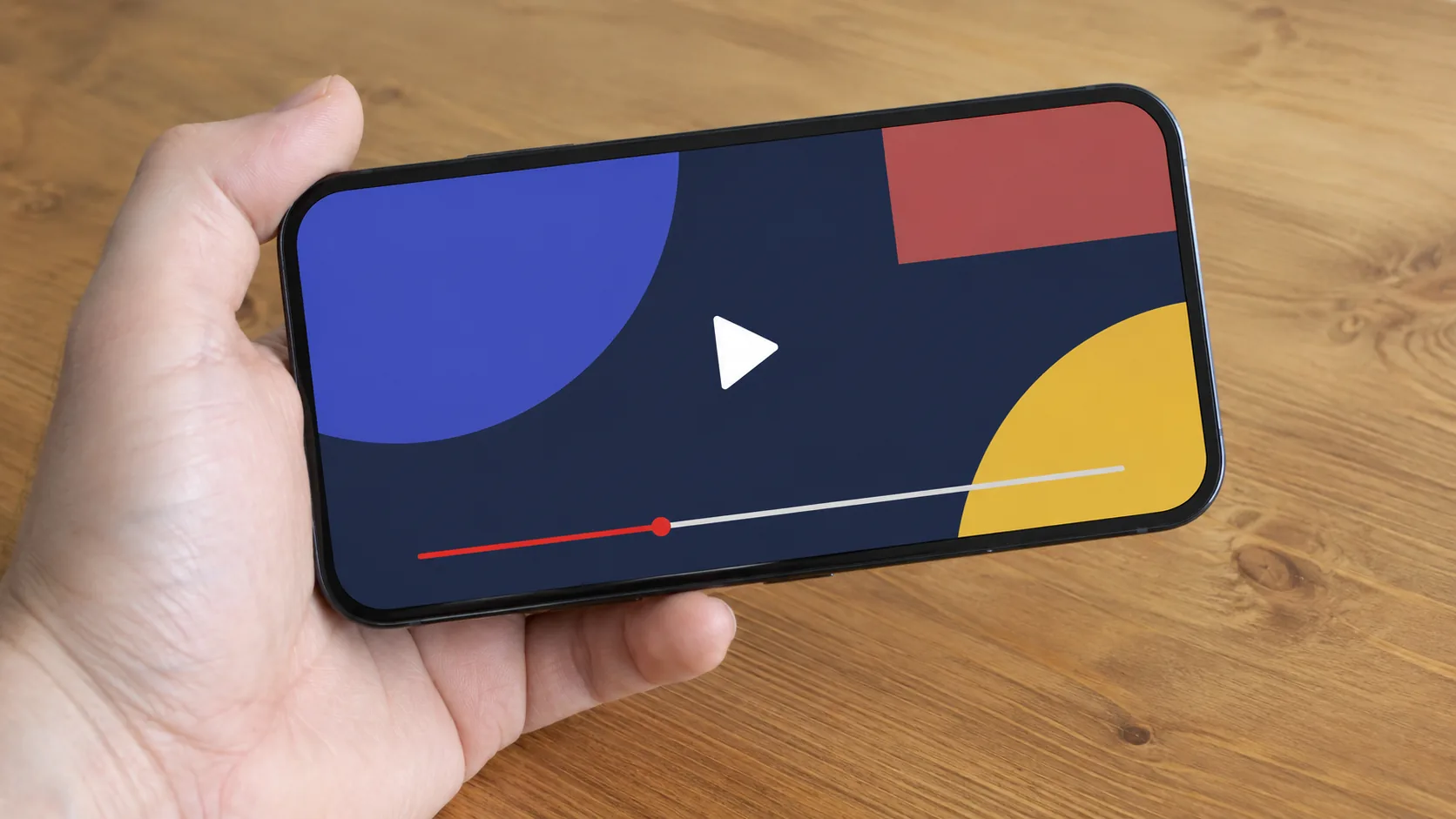 A generic smartphone showing an unlabeled video frame with a simple progress bar, held above a plain table with no visible brand